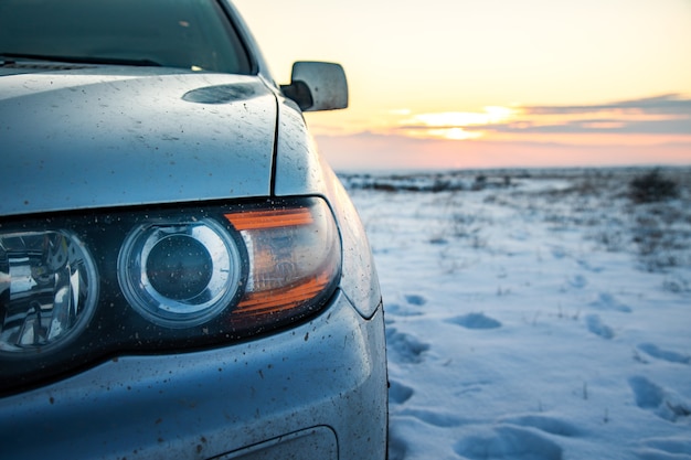 Coche en un paisaje nevado al atardecer