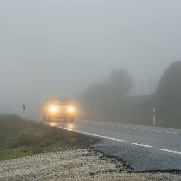 Foto coche pasando por el camino de la montaña en un día muy brumoso y lluvioso