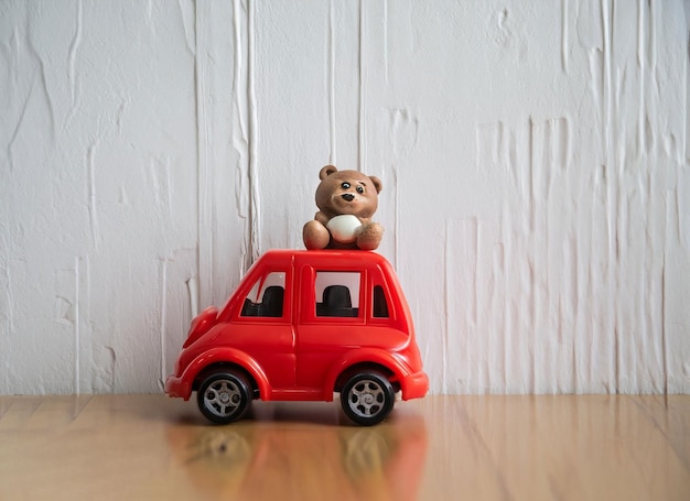 Foto coche de plástico en pared blanca con oso.