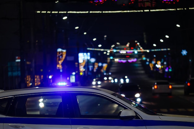 Coche de policía con luces en la vista lateral del primer plano de la ciudad de noche con enfoque selectivo