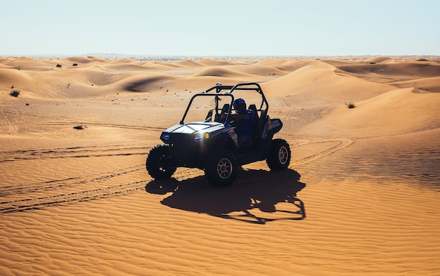 Coche quad buggy en las dunas de arena con reflejos de sol en los faros, diviértete en el tour de safari extremo de Dubai