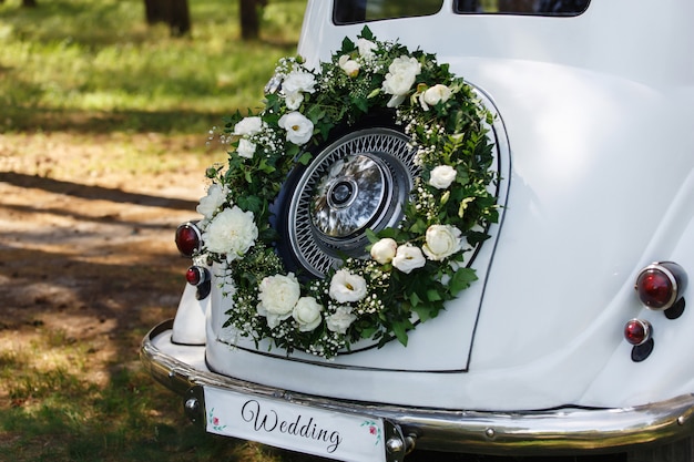 Coche recién casado con inscripción "Boda" y corona de flores frescas