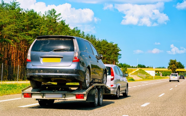 Coche con remolque de remolque bajo en carretera. Vehículos de automóviles con transportador de transporte Carrier en la calzada. Logística de transporte europea en el transporte de trabajo de acarreo. Transporte con conductor en carretera.