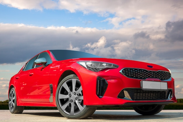 Coche rojo en un fondo del cielo azul con las nubes blancas.