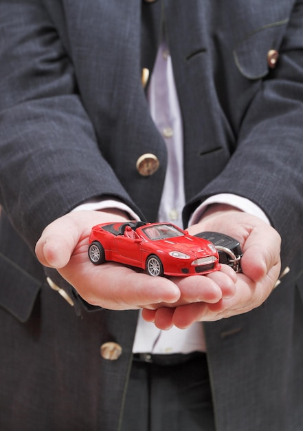 Coche rojo y llave en mano del vendedor.