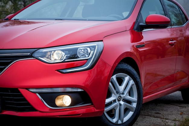 Un coche sedán de color rojo está aparcado en la carretera