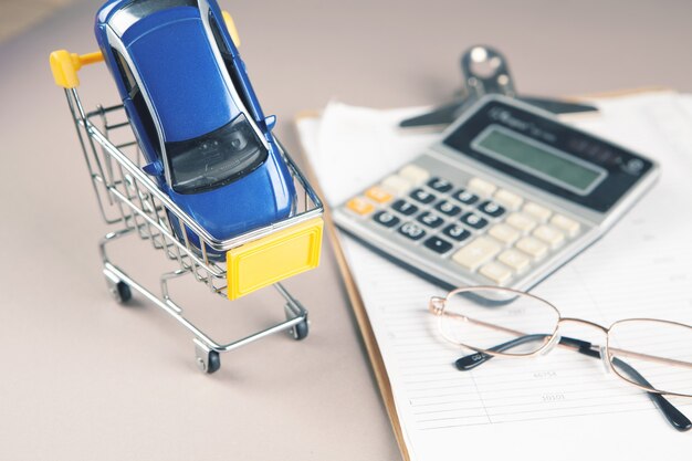 Coche sobre la mesa en una canasta, calculadora y papel