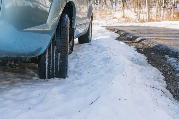 Coche SUV en la carretera de asfalto cubierto de nieve en el bosque