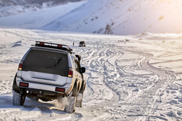 Coche SUV conduce a través de un valle de montaña cubierto de nieve con nieve profunda después de una tormenta de nieve