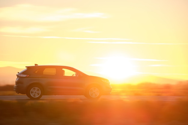 Coche SUV conduciendo rápido en la carretera interurbana al atardecer. Tráfico de la carretera en la noche.