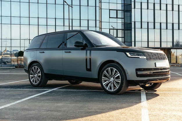 Coche SUV de lujo estacionado en el fondo de un edificio de vidrio