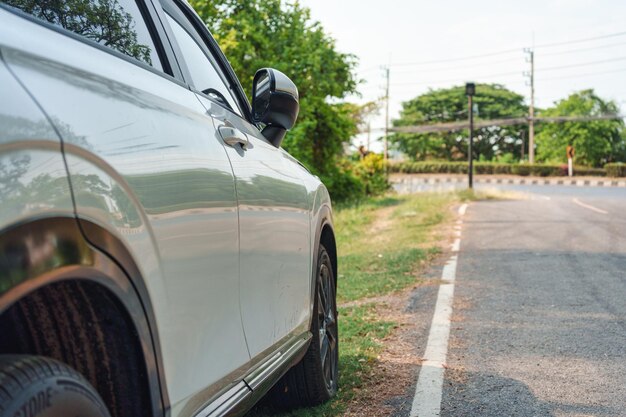 Coche SUV moderno blanco con asfalto manchado estacionado en la carretera