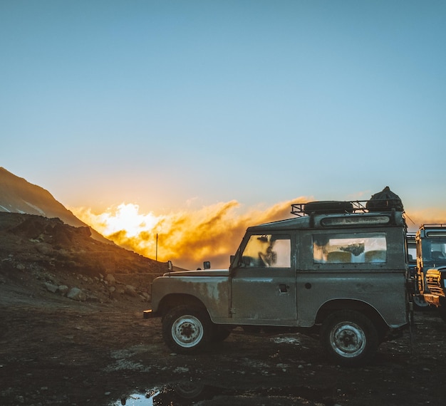 Foto coche en tierra contra el cielo durante la puesta de sol