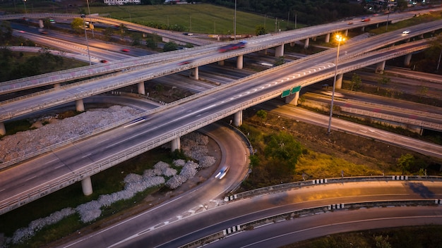 Coche de tráfico del movimiento de la exposición larga del paisaje crepuscular en el intercambio de la autopista en Tailandia