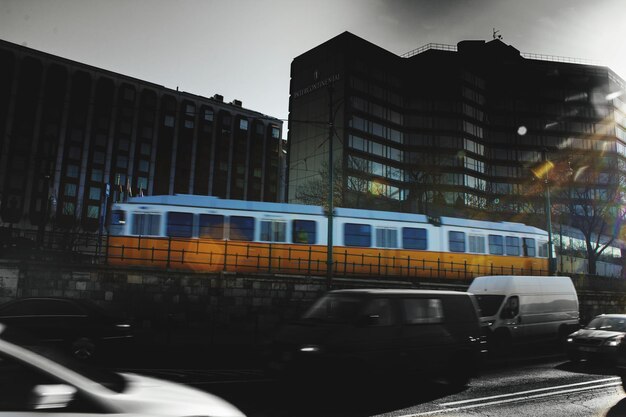 Foto coches en la carretera por tren y edificios en la ciudad contra el cielo