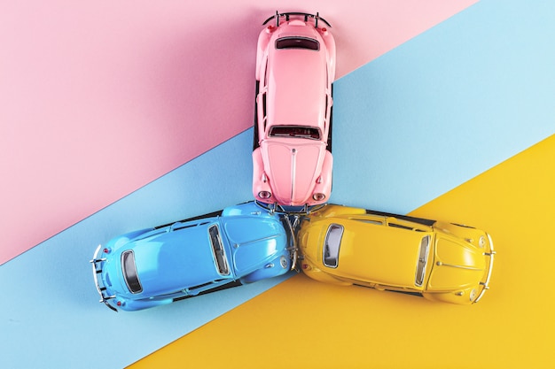 Coches de juguete en accidente sobre un fondo colorido pastel.