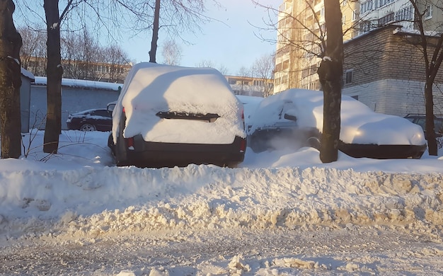 Coches bajo la nieve en el estacionamiento de la ciudad