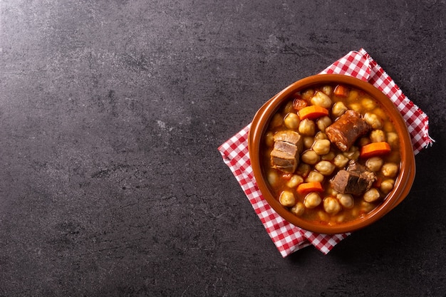 Cocido madrileÃ ± o tradicional español en un recipiente rústico sobre fondo negro