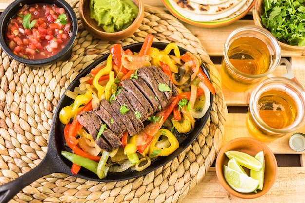 Cocina al aire libre. Filete de fajitas con pimientos morrones y cebolla amarilla en una sartén de hierro fundido para fajitas.