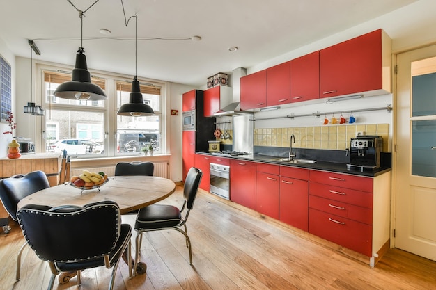 Foto una cocina con armarios rojos y una mesa y sillas.