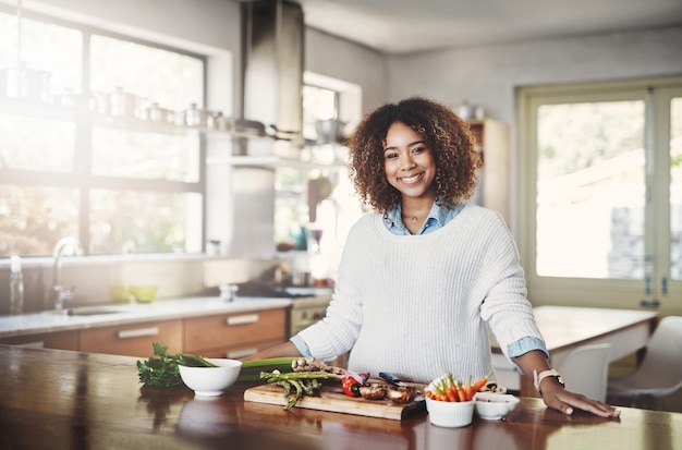 Cocina de bienestar y un estilo de vida saludable en casa con una mujer feliz que comienza un viaje de pérdida de peso Retrato de una mujer sonriendo preparando una comida nutritiva con verduras orgánicas en una cocina