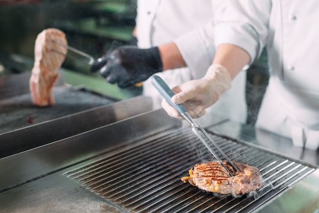 Cocina carne asada en la estufa en la cocina de un restaurante u hotel.