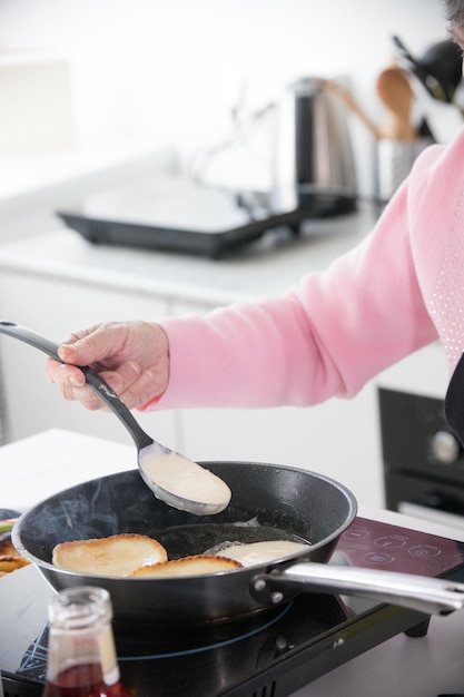 Cocina casera una anciana friendo panqueques