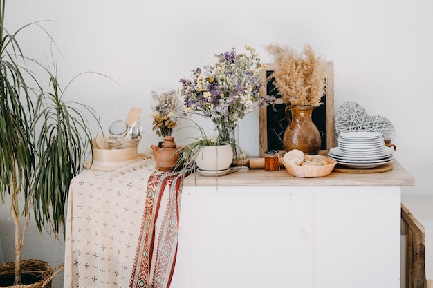 Foto cocina casera decoración interior rústica de apartamento con mesa, arcilla y utensilios de madera, flores.