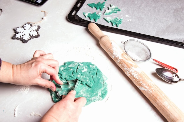 Cocina casera de pan de jengibre navideño Las manos de las mujeres hacen pan de jengibre con masa