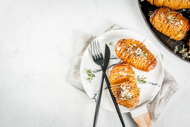 Cocina casera tradicional estadounidense. La dieta vegana. Patatas Hasselback caseras con hierbas frescas y queso.