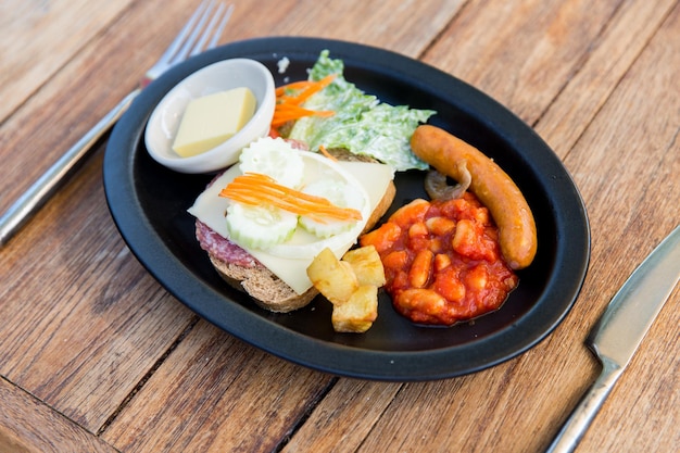 cocina, cocina asiática y concepto de comida - plato con salchicha, sándwich y guarnición en una mesa de madera en el restaurante