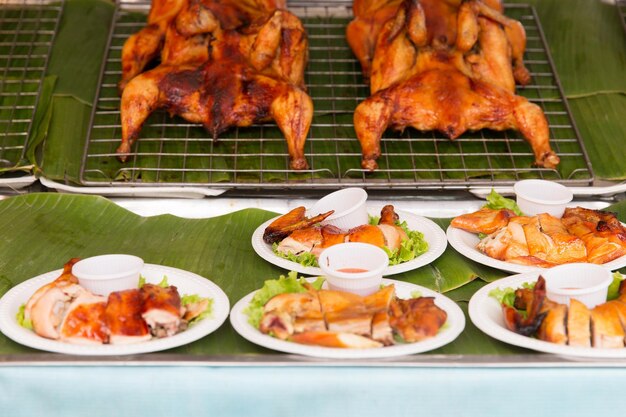 cocina, cocina asiática, venta y concepto de comida - pollo a la parrilla o frito en un plato en el mercado callejero