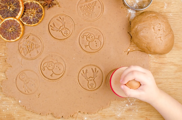 Cocina creativa navideña de galletas caseras con las manos de los niños en una madera.