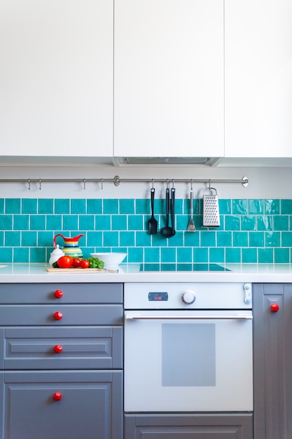 Foto la cocina cuenta con gabinetes frontales planos de color gris oscuro combinados con encimeras de cuarzo blanco y un azulejo azul brillante.