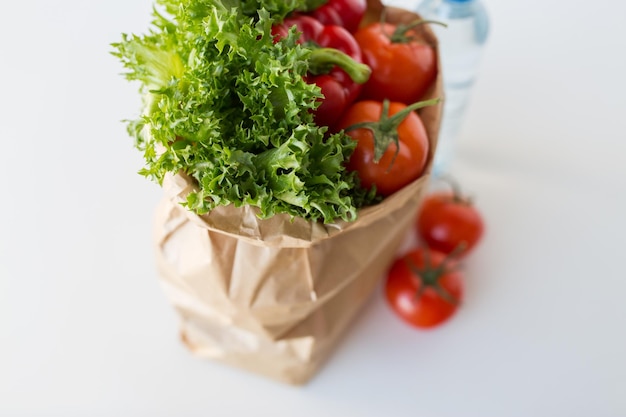 cocina, dieta, comida vegetariana y concepto de alimentación saludable: cierre de una bolsa de papel con verduras frescas y jugosas maduras y verduras en la mesa de la cocina en casa