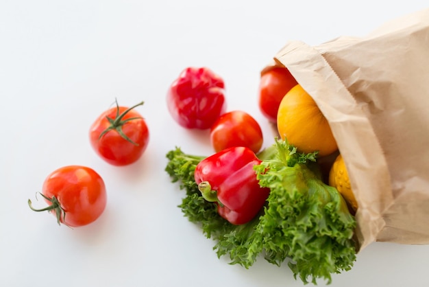 cocina, dieta, comida vegetariana y concepto de alimentación saludable: cierre de una bolsa de papel con verduras frescas y jugosas maduras y verduras en la mesa de la cocina en casa