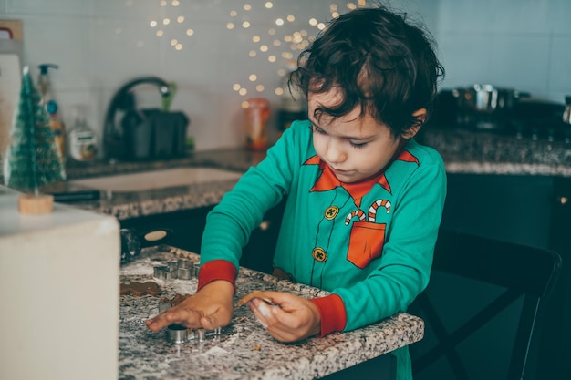 La cocina está llena de risas y alegría. El niño y la madre preparan con entusiasmo pan de jengibre de Navidad.