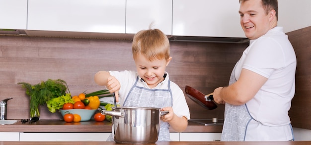 Cocina familiar en el hogar papá con hijo cocina la cena para mamá diviértete