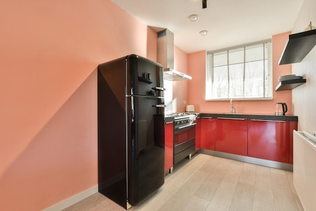 Una cocina con gabinetes rojos y un refrigerador negro.