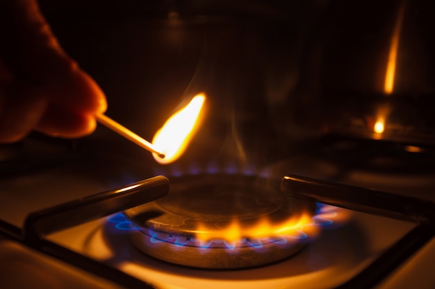 Foto cocina de gas con fuego de propano. un hombre encendiendo la estufa de gas con una cerilla.