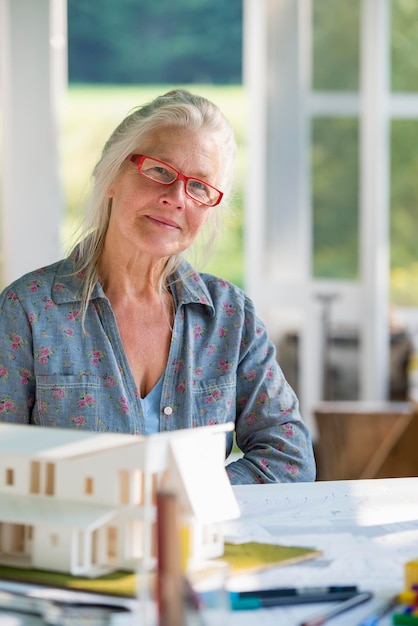 La cocina de una granja La maqueta de una casa sobre la mesa El diseño de una casa Una mujer sentada sosteniendo un bolígrafo