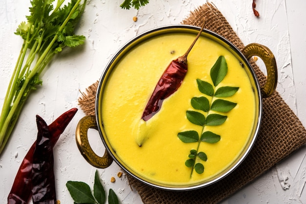 Cocina india Kadhi - Curry vegetariano hecho de suero de leche y harina de garbanzo. servido en un cuenco o Karahi sobre fondo cambiante, enfoque selectivo