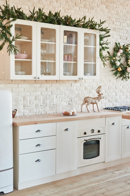 Cocina interior ligera con decoración navideña y árbol. Cocina blanca en estilo clásico. Navidad en la cocina. Cocina luminosa en tonos blancos con Navidad.