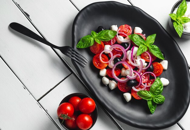 Foto cocina italiana ensalada fresca de caprese italiana con mozzarella y tomates en un plato oscuro