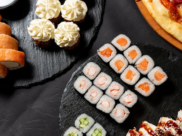 cocina japonesa varios tipos de rollos de sushi con pizza en una pancarta de sushi de fondo negro