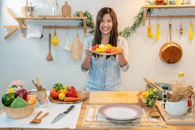 cocina joven asiática y presentar la ensalada en el lugar en la cocina moderna