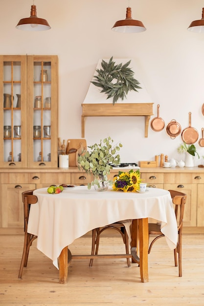 Cocina de madera escandinava de diseño de interiores con mesa redonda y sillas con platos de utensilios