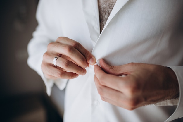 Cocina de la mañana, hermoso novio, vestido y preparándose para una boda, chaqueta con botones a presión.