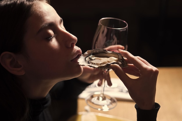 Cocina marinera y mediterránea con mejillones con cáscara. mariscos de ostra en mano de mujer con vino tinto en copa.