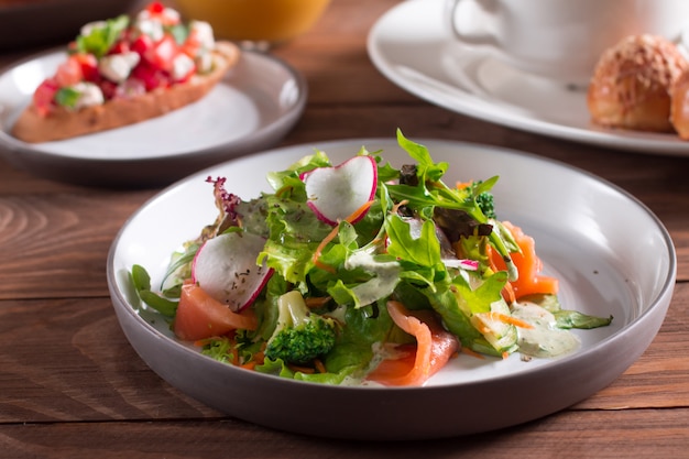 Cocina mediterranea. Ensalada. Rebanadas de salmones con la ensalada de las verduras frescas en una placa.